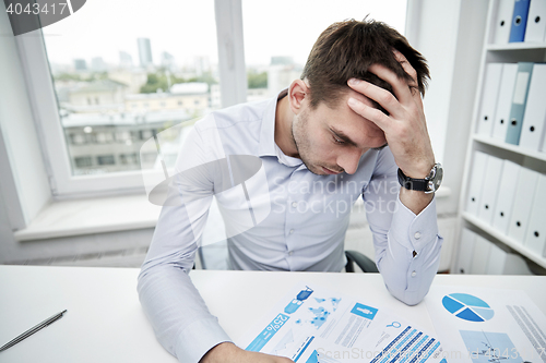 Image of stressed businessman with papers in office