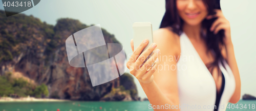 Image of young woman taking selfie with smartphone on beach