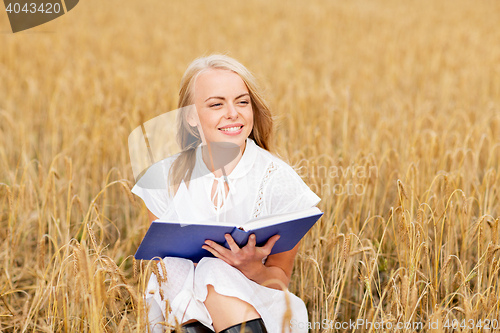 Image of smiling young woman reading book on cereal field