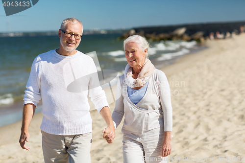 Image of happy senior couple holding hands on summer beach