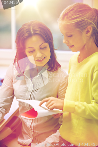 Image of school girl with notebook and teacher in classroom