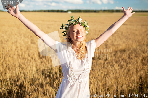 Image of happy young woman in flower wreath on cereal field