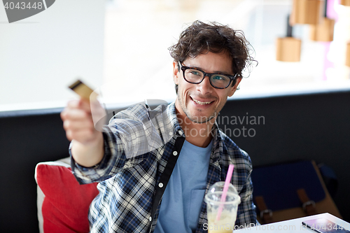 Image of happy man paying with credit card at cafe