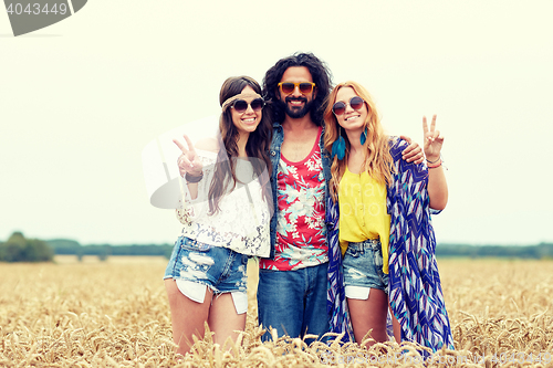 Image of happy young hippie friends showing peace outdoors