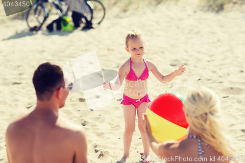 Image of happy family playing with inflatable ball on beach
