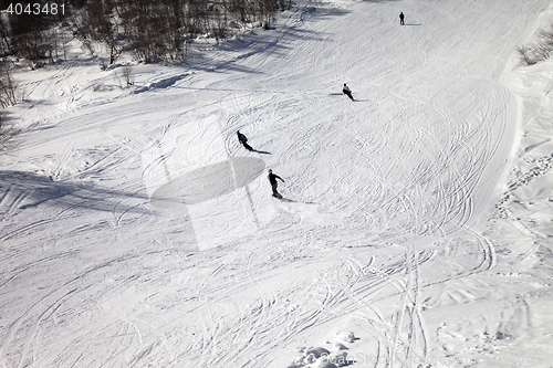 Image of Skiers and snowboarders on ski slope at sun winter day