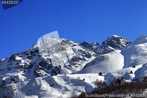 Image of Snowy rocks and off-piste slope in sunny morning