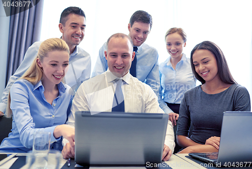 Image of smiling business people with laptop in office
