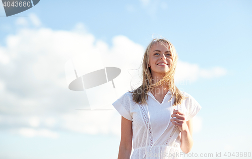Image of smiling young woman in white dress over blue sky