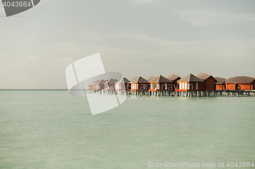 Image of bungalow huts in sea water on exotic resort beach