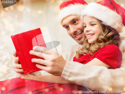 Image of smiling father and daughter reading book