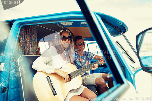 Image of smiling hippie couple with guitar in minivan car