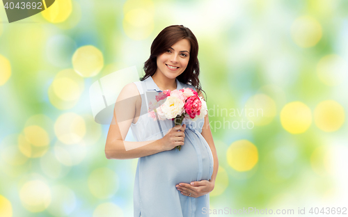 Image of happy pregnant woman with flowers touching belly