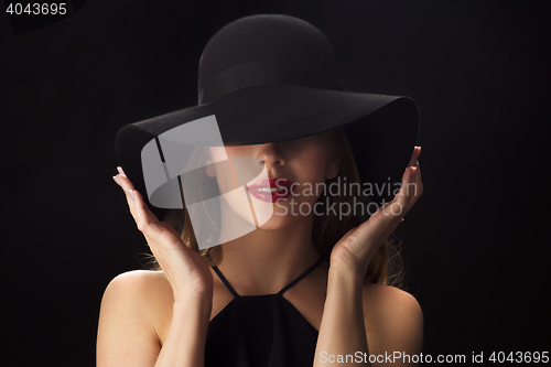 Image of beautiful woman in black hat over dark background