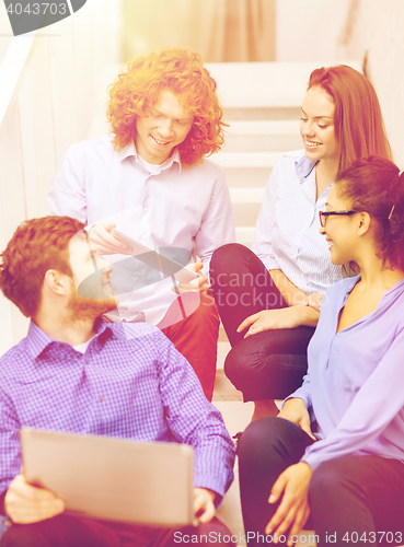 Image of team with laptop and tablet pc on staircase