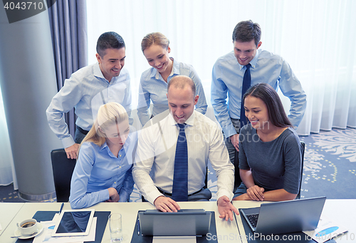 Image of smiling business people with laptop in office