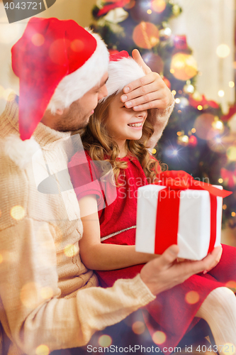 Image of smiling father surprises daughter with gift box