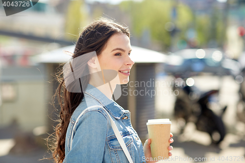 Image of happy young woman drinking coffee on city street