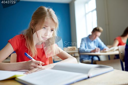 Image of student girl with book writing school test