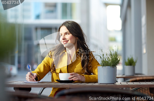 Image of happy woman with notebook drinking cocoa at cafe