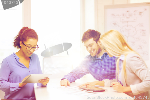 Image of smiling team with table pc and papers working