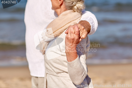 Image of close up of happy senior couple hugging on beach