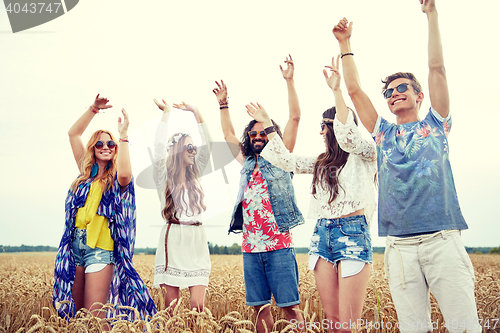 Image of happy young hippie friends dancing outdoors