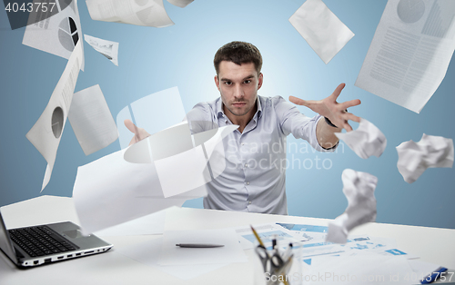 Image of angry businessman throwing papers in office