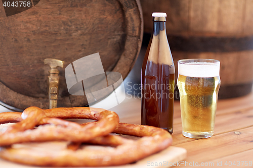 Image of close up of beer barrel, glass, pretzel and bottle
