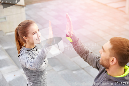 Image of smiling couple making high five on city street