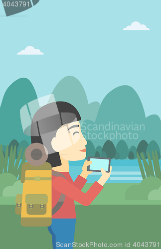 Image of Woman with backpack taking photo.