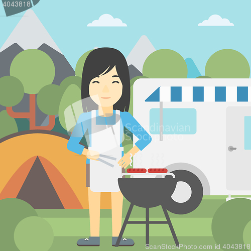 Image of Woman having barbecue in front of camper van.