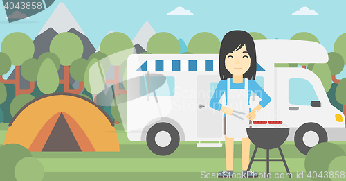 Image of Woman having barbecue in front of camper van.