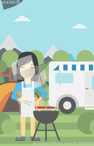 Image of Woman having barbecue in front of camper van.