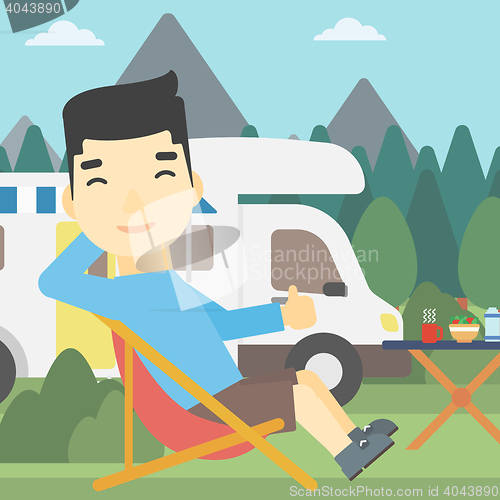 Image of Man sitting in chair in front of camper van.