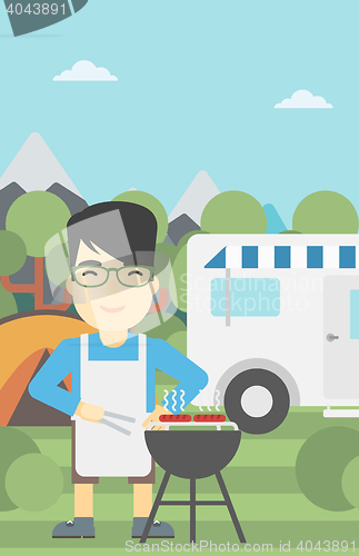 Image of Man having barbecue in front of camper van.