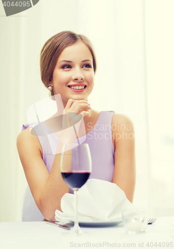 Image of smiling woman with glass of whine waiting for date
