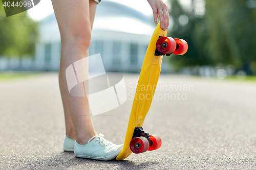 Image of close up of female feet with short skateboard