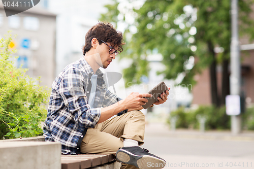 Image of man with tablet pc sitting on city street bench