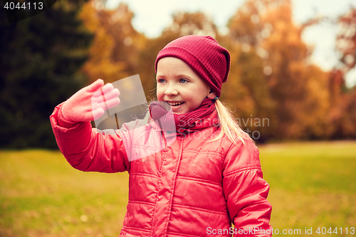Image of happy little girl waving hand in autumn park