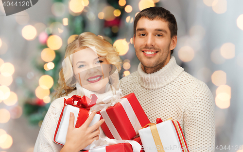 Image of happy couple in sweaters holding christmas gifts