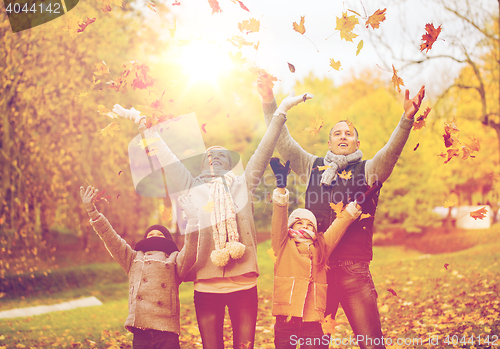 Image of happy family playing with autumn leaves in park