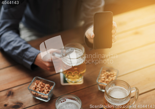 Image of close up of friends with smartphone and beer