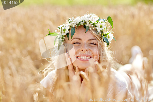 Image of happy woman in wreath of flowers on cereal field