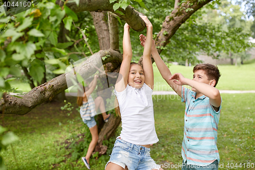 Image of happy kids hanging on tree in summer park