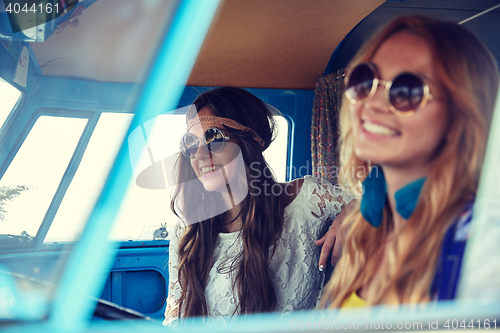 Image of smiling young hippie women driving minivan car