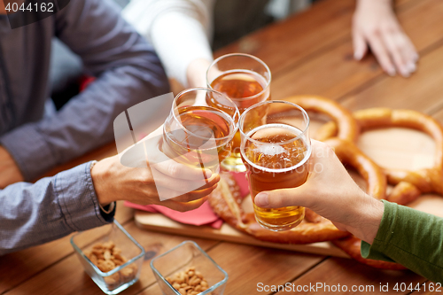 Image of close up of hands clinking beer at bar or pub