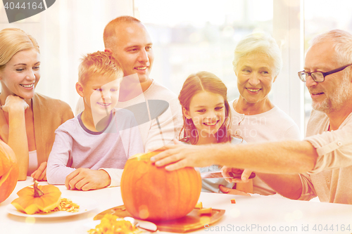 Image of happy family sitting with pumpkins at home