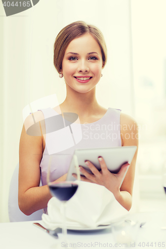 Image of smiling woman with tablet pc computer at resturant