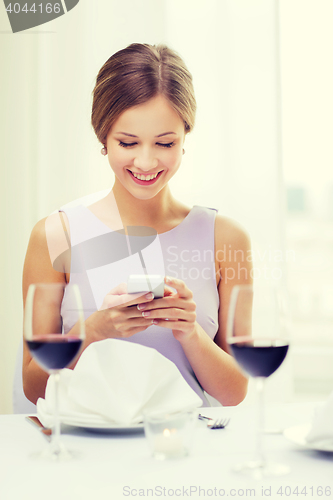 Image of smiling woman with smartphone at resturant